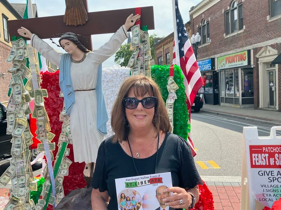 Linda Locantore, committee chair for the Saint Liberata Feast, stands in front of a statue of Saint Liberata. People donated dollar bills to Our Lady of Mt. Carmel Church and St. Francis de Sales Church.